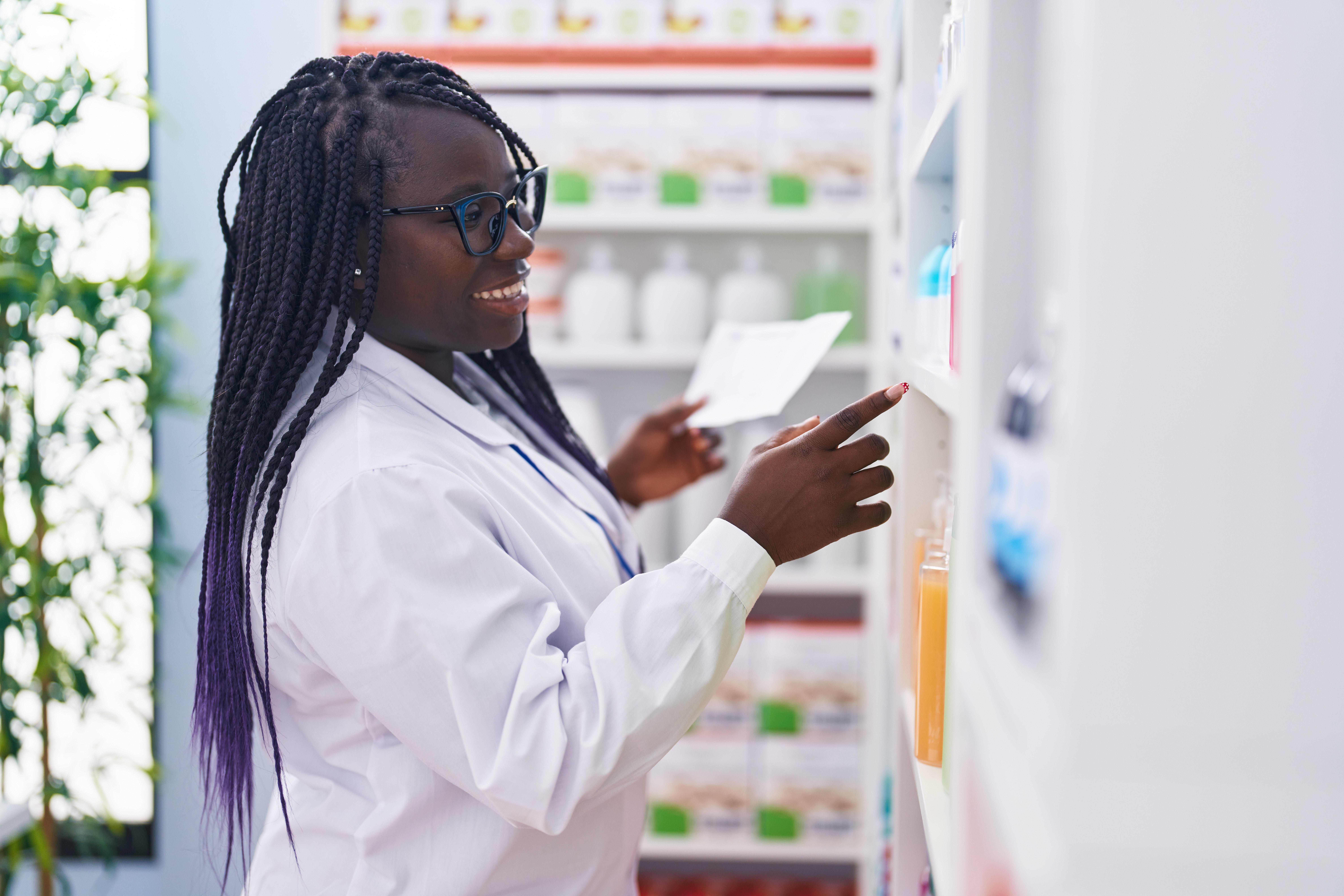 african-american-woman-pharmacist-reading-prescription-standing-by-shelving-pharmacy