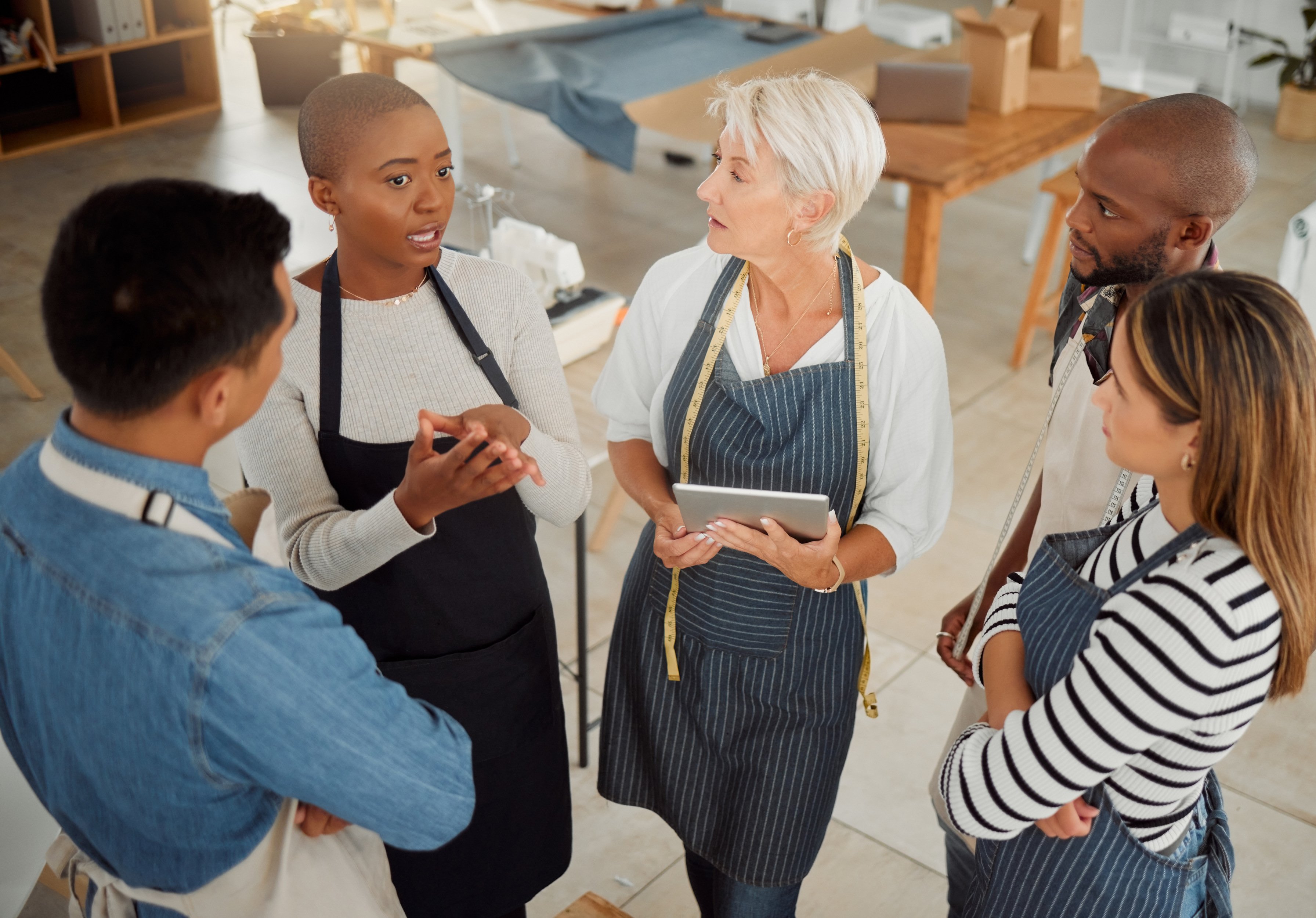 creative-diverse-discussion-group-fashion-designer-planning-with-tablet-talking-workshop-tailor-teamwork-people-business-meeting-apron-conversation-design-studio