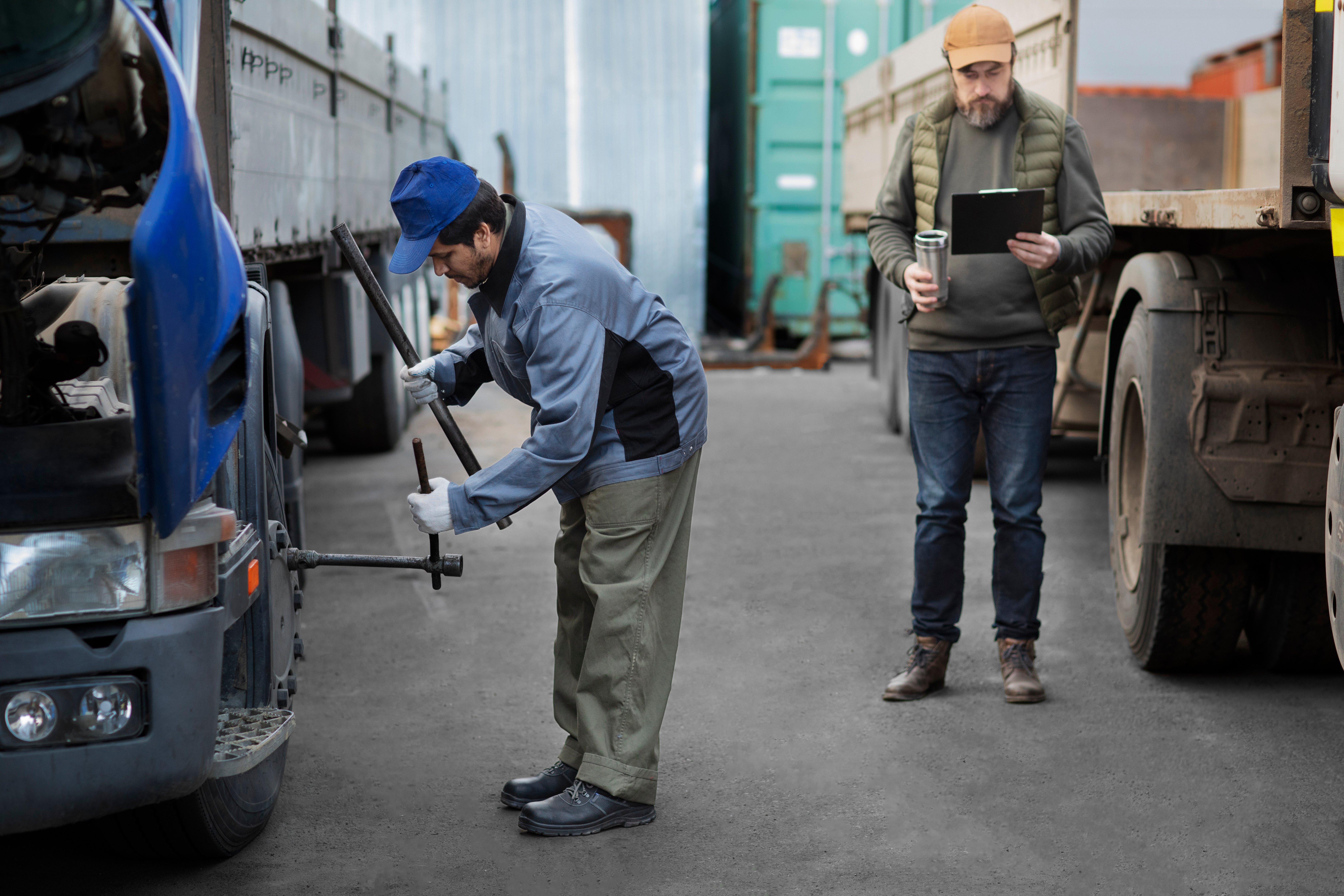 full-shot-mechanic-checking-truck-outdoors