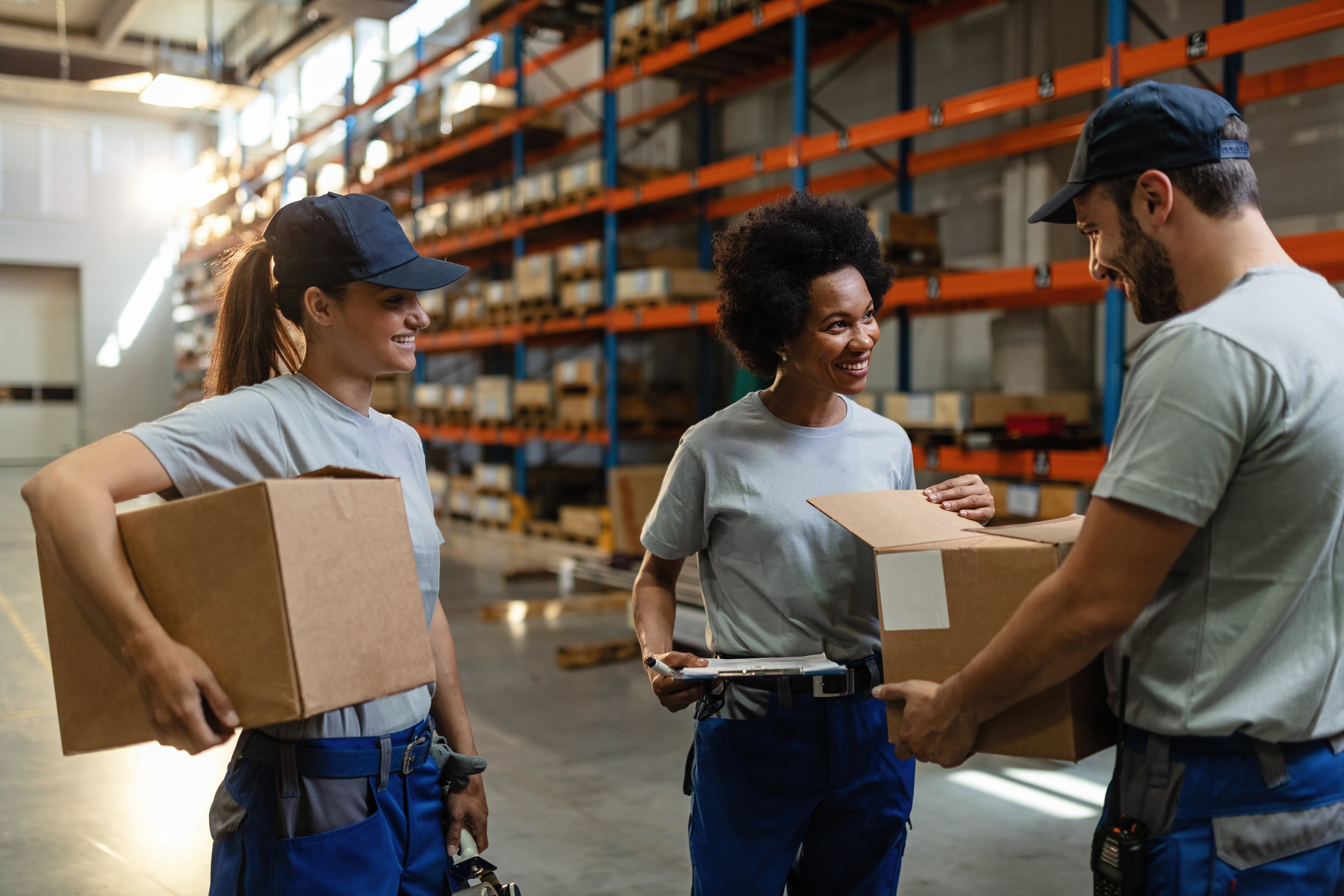 happy-african-american-woman-her-coworkers-examining-packages-while-working-distribution-warehouse