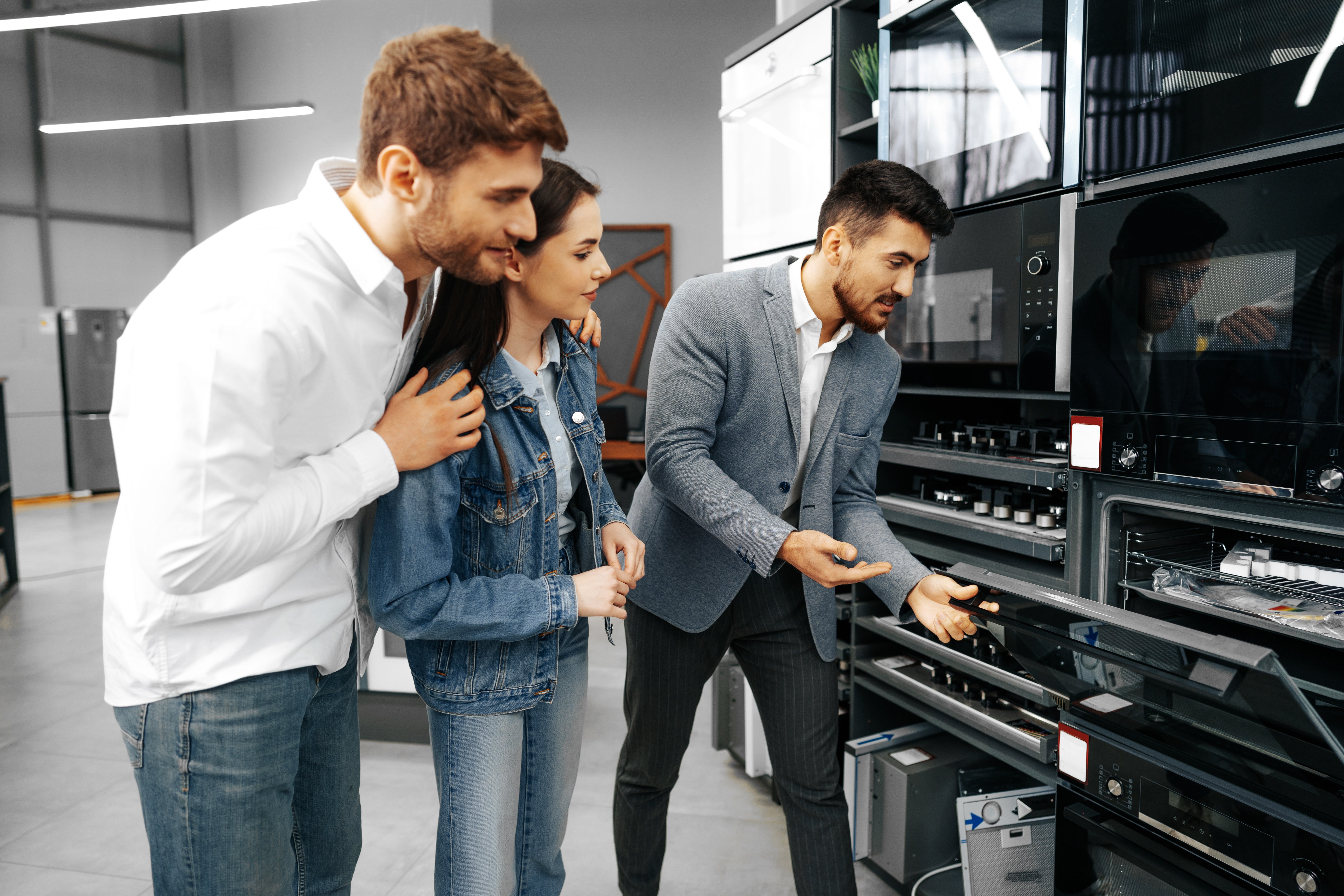 male-shop-assistant-helps-young-couple-choose-new-home-appliance