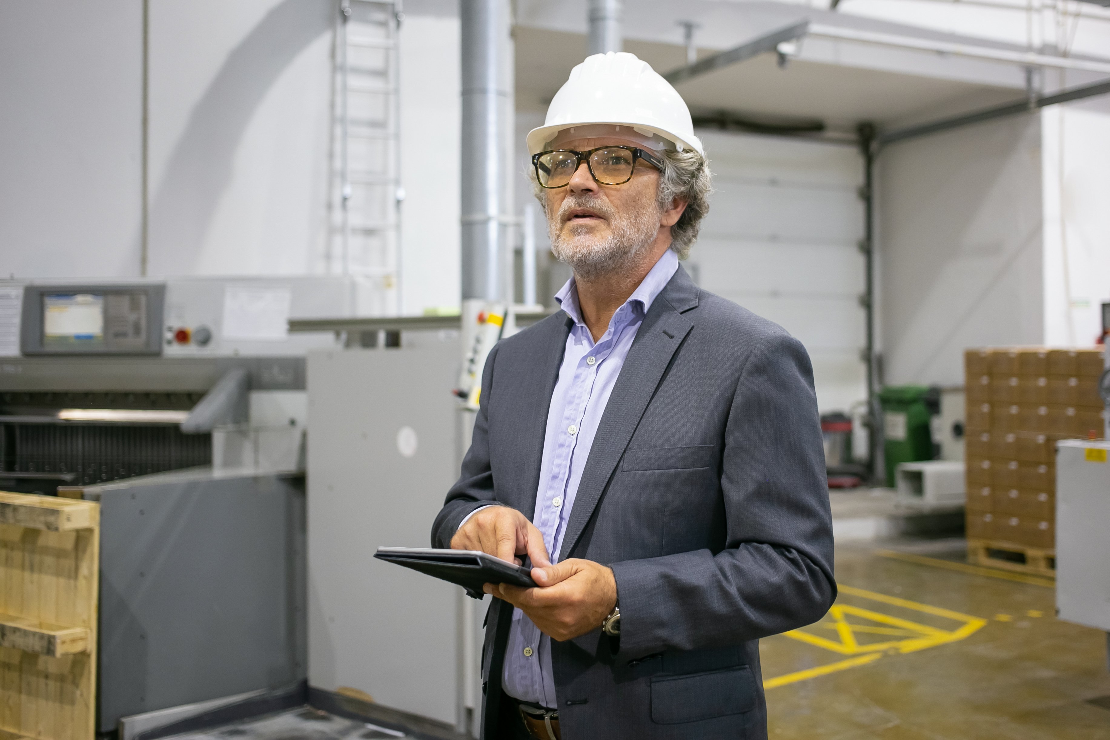 pensive-man-protective-helmet-holding-tablet-looking-away