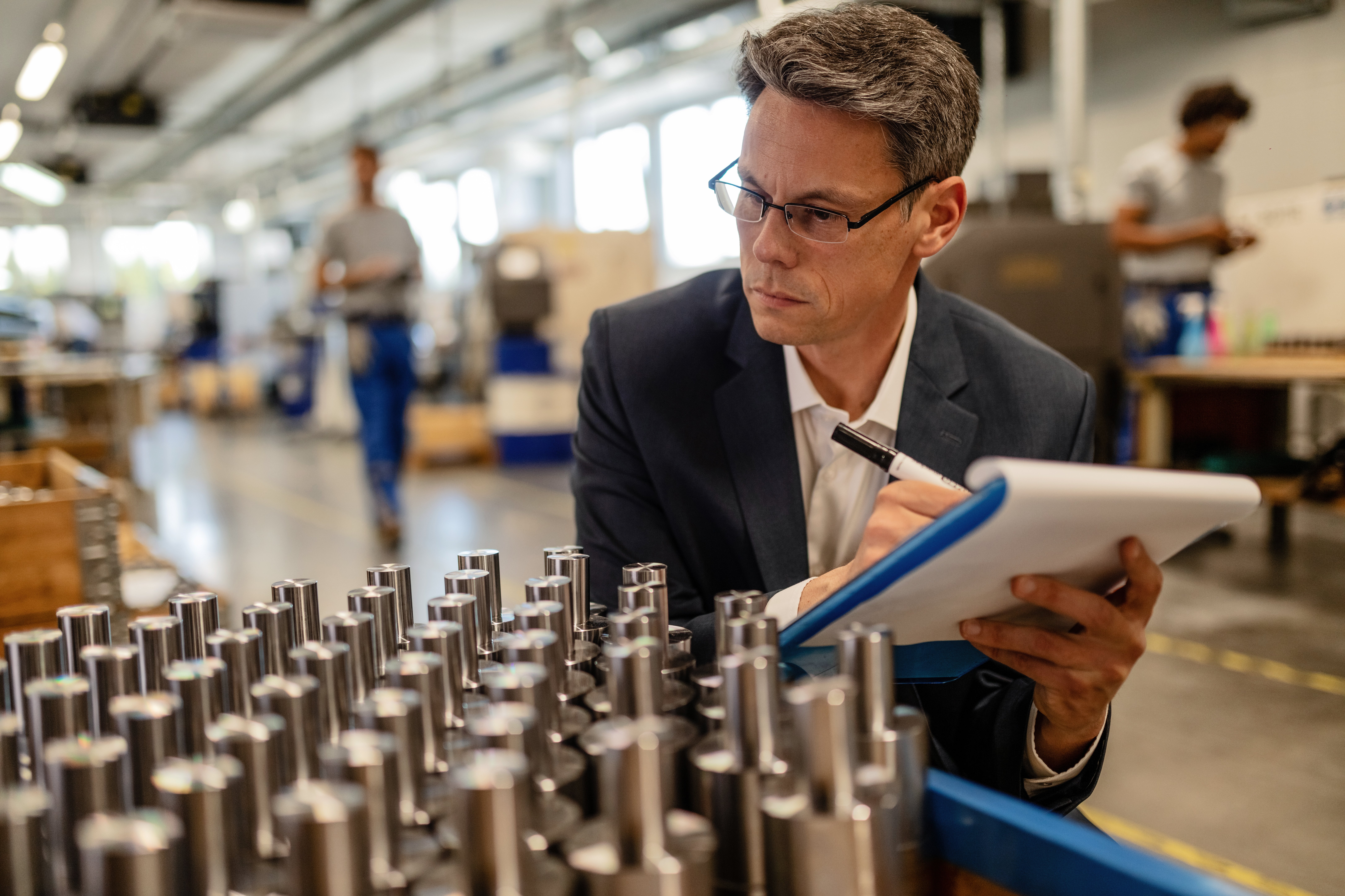quality-control-inspector-writing-reports-while-analzying-manufactured-steel-rod-cylinders-industrial-building