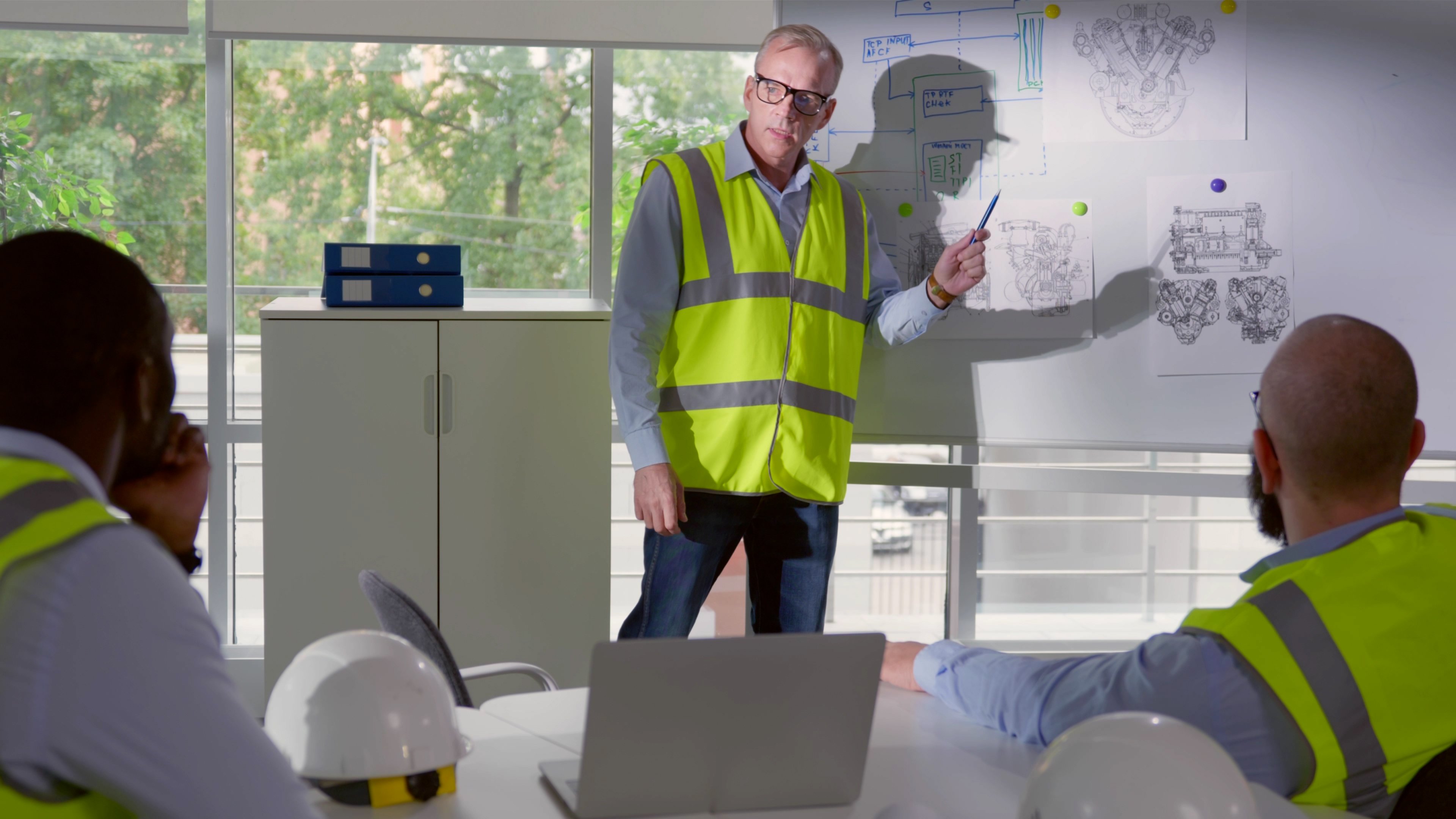senior-engineer-making-presentation-diverse-team-modern-office