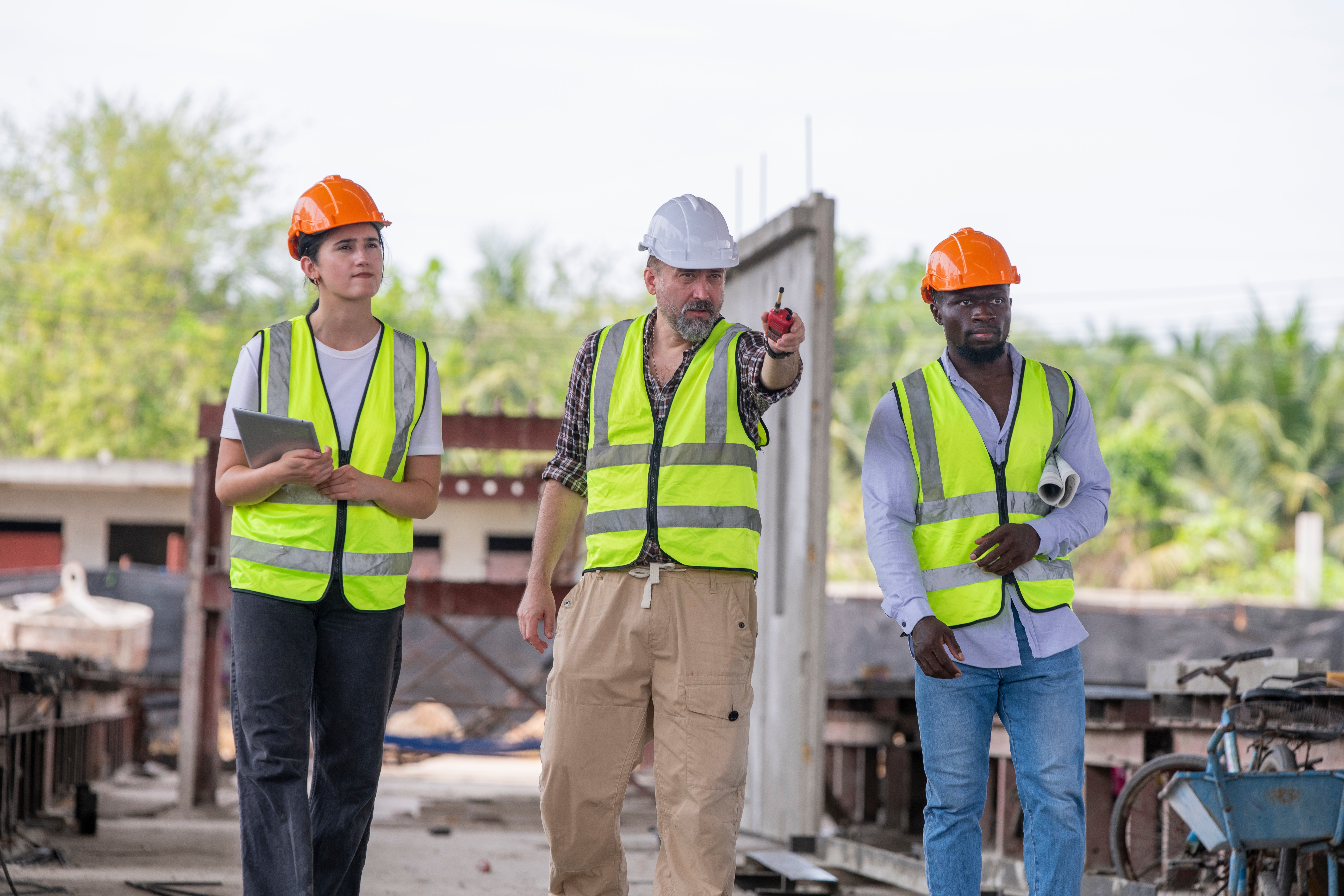 three-people-wearing-safety-vests-construction-vests-are-standing-construction-site